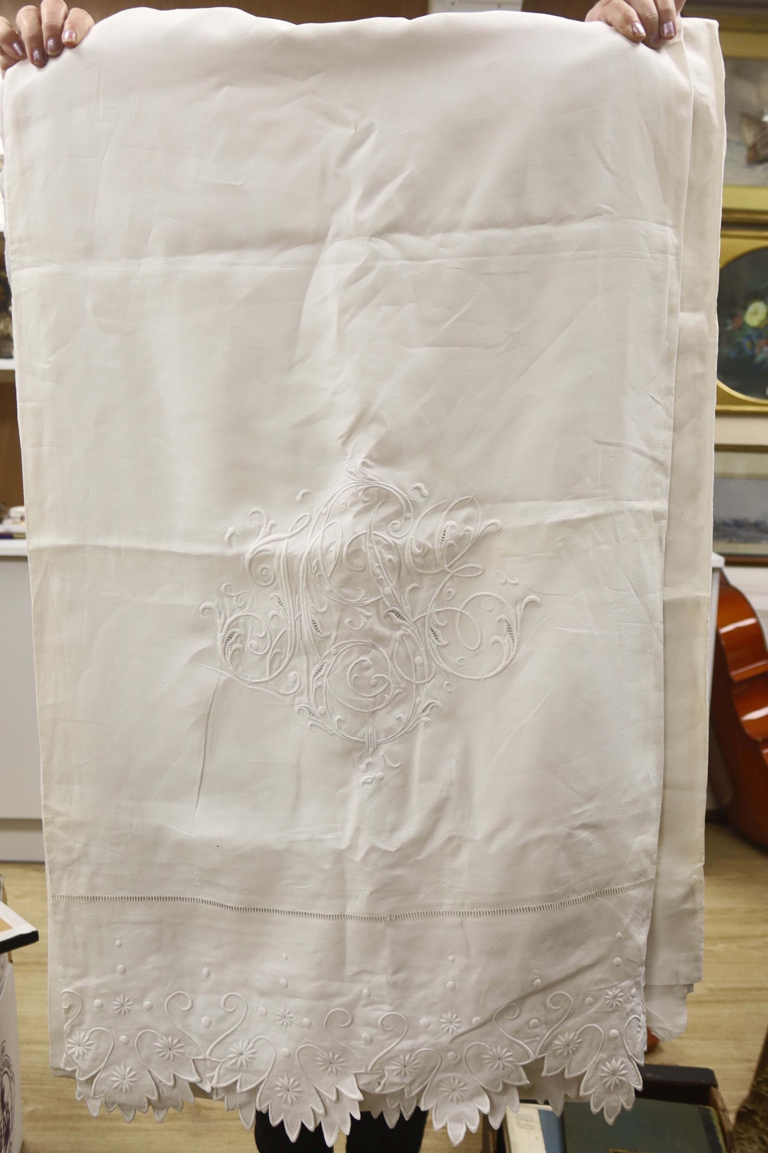 A tin trunk containing a scalloped linen sheet with embroidered monogram linen crochet tablecloths, chemical lace cloth etc.